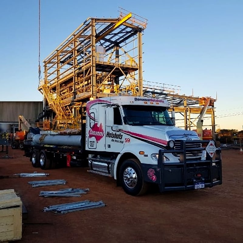 Dananni Hotshots prime mover delivering steel to a mine site at dusk